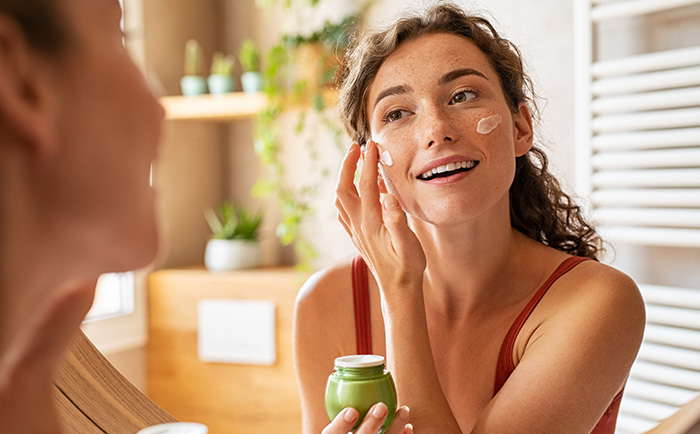 Gesichtspflege aus dem Online Shop für Naturkosmetik Eine Frau cremt sich das Gesicht mit Naturkosmetik aus dem Online Shop ein