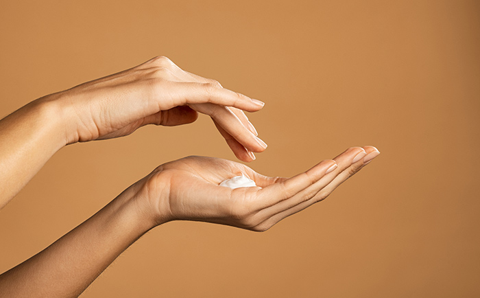 Handpflege aus dem Online Shop für Naturkosmetik Eine Frau cremt sich die Hände mit Naturkosmetik aus dem Online Shop ein